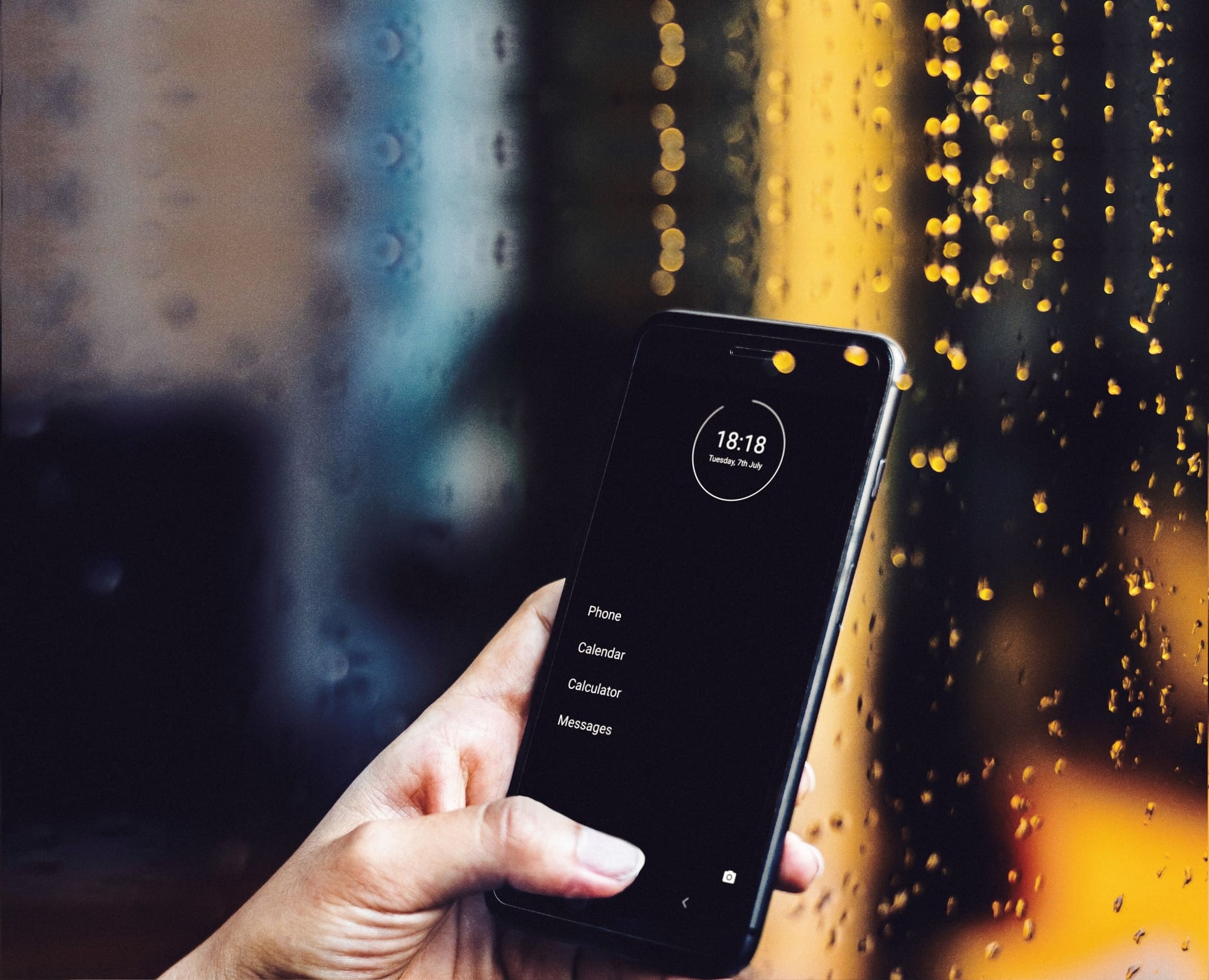 minimal phone launcher on an android phone in front of a rainy window