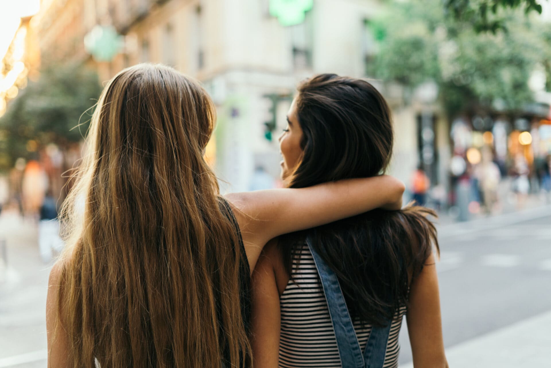 Rearview of a blonde female putting her arm around her friend